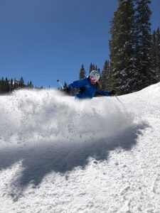 Kristina Mitchel sprays snow while skiing in this photo.