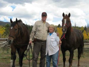 Bob Bryant and Connie Kassel stand side by side between two horses.