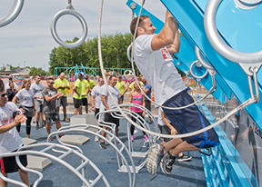 Man does chinups on exercise equipment during a competition at outdoor fitness court.