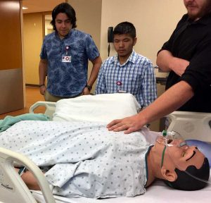 students stand by a patient simulation dummy
