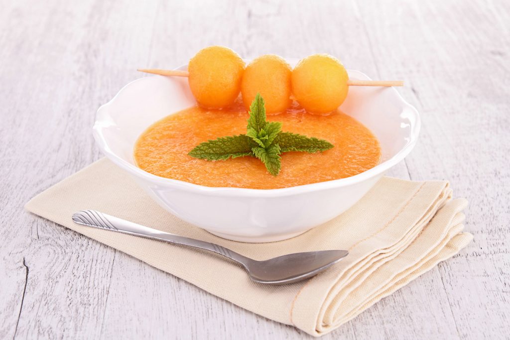 photo of cantaloupe soup in a bowl with cantaloupe balls on the edge
