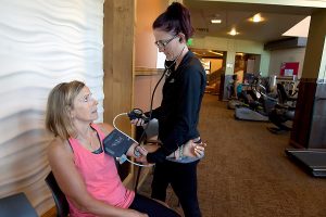 Therapist takes blood pressure of patient in the gym.