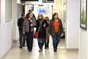 Nurse walks patient's family members down a hospital corridor.