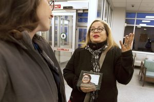 Patient's sister holds photo of patient while speaking with nurse in hospital
