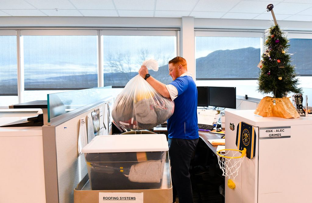 Frostbite survivor Alec Grimes sorts warm gear at his cubicle at Johns Manville in Littleton.