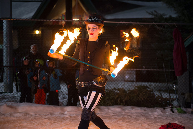 A woman twirls a fiery baton in this photo.