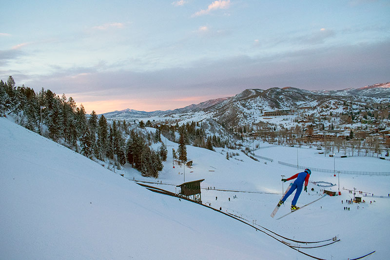 A skier flies off a Nordic ski jump in this photo.