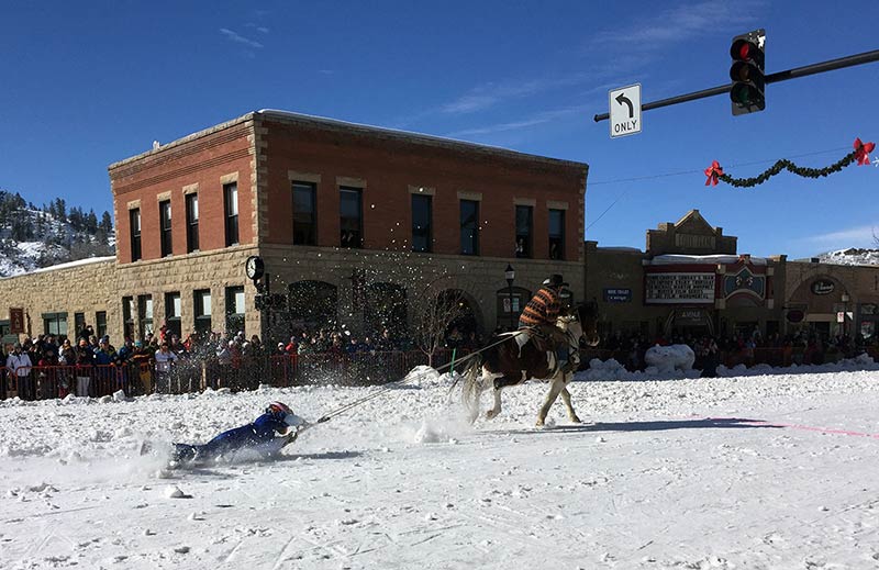 This is a photo of a shovel race, in which a participant rides on a shovel pulled by a horse on a snow-covered street.