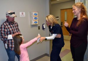 After being diagnosed with colon cancer, Keith returns to thank the UCHealth Urgent Care staff. Here is daughter hands one nurse a tissue because the reunion made her cry.
