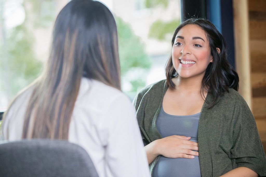 A pregnant woman talks with a care provider in this photo.