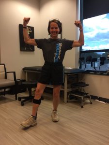 Lane Malone raises her arms with excitement after being fitted for an ankle-foot orthosis in this phohto.