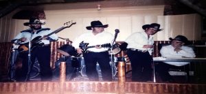 Old photograph of Jack Silva playing country music with bandmates on stage.