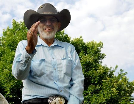 Jack Silva giving a wave atop a tractor during a parade.
