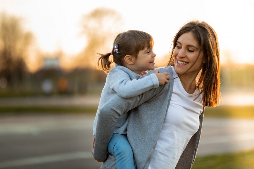 A mother gives her young daughter a piggyback ride in this photo.