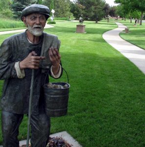 sculpture of old man carrying bucket of potatoes at a park.