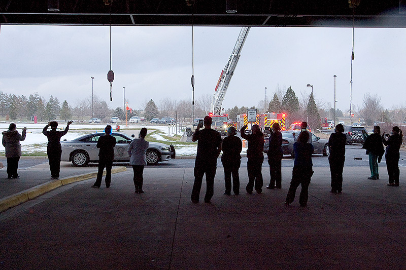 health care workers recieve thanks from local emergency responders in a parade while they stank under the hospital's ambulance bay.