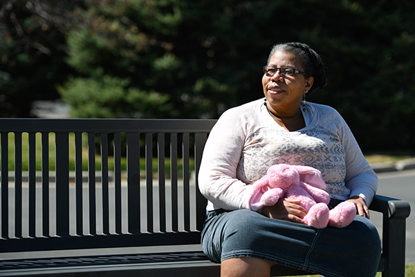 African American COVID-19 survivor Ravi Turman sits on a park bench and enjoys the feel of the sun on her face.