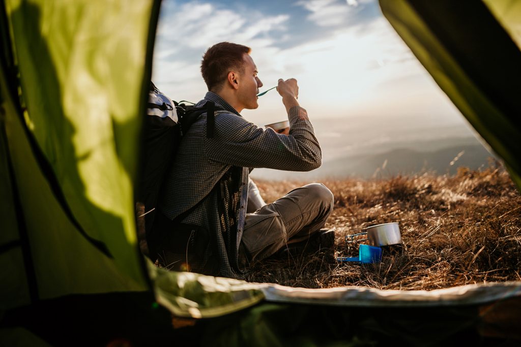 A man enjoys healthy camping meals outside his tent.