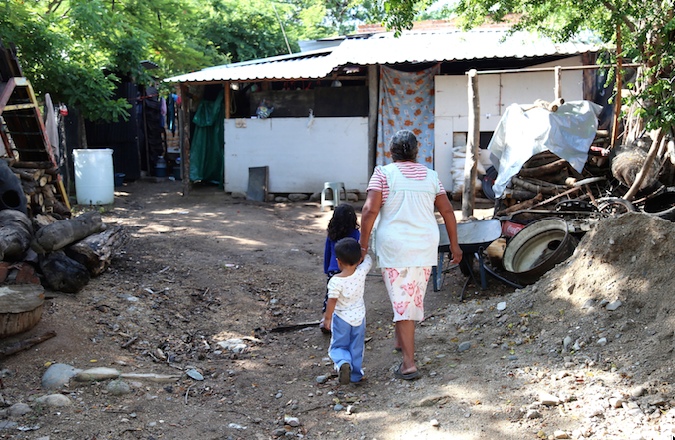 Una mujer camina con sus nietos hacia su casa rentada en una comunidad de Juan R. Escudero, donde se refugia luego de huir de su pueblo en el municipio de Chilapa el 6 de junio, a causa de la violencia por la disputa del territorio entre Los Ardillos y Los Rojos. Foto: Jesús Eduardo Guerrero