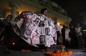 Una activista cubre su cuerpo con retratos de mujeres asesinadas, en el mitin en el Zócalo de Chilpancingo para exigir justicia por las mujeres víctimas de feminicidio en el país y en el estado. Foto: Jesús Eduardo Guerrero