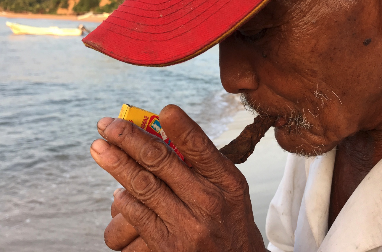 Don Genaro de los Santos Silva, pescador de 78 años enciende su tabaco antes de zarpar al mar, como lo ha hecho todas las tardes de sus últimos 38. Foto: Lenin Ocampo Torres