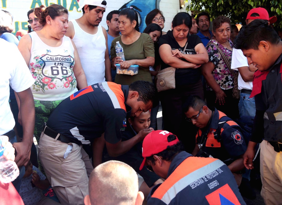 Socorristas de la Secretaría de Protección Civil estatal, atienden a una alumna en Chilpancingo, que se desvaneció mientras esperaba participar en el desfile conmemorativo del centésimo sétimo aniversario de la Revolución Mexicana, cuando la diputada federal del PRI, Beatriz Vélez Núñez dirigía un mensaje a los asistentes. Foto: Jessica Torres Barrera