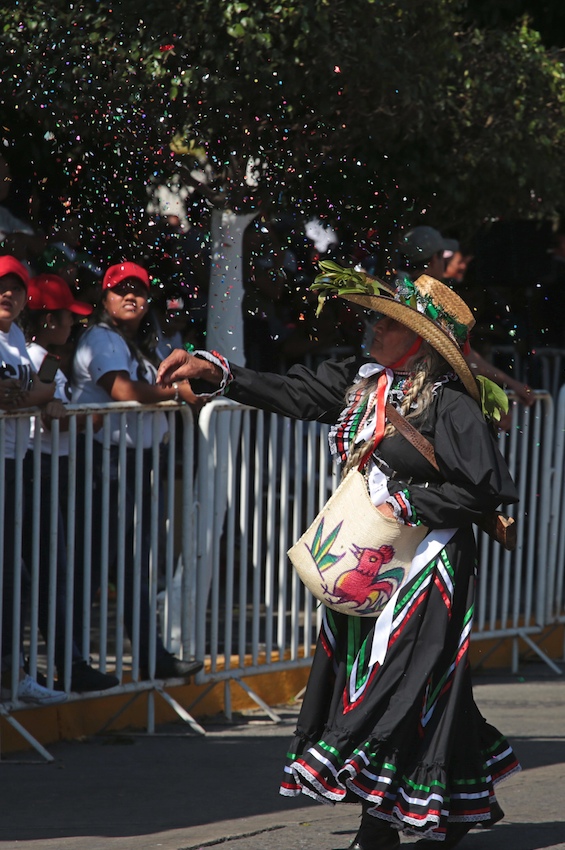 Una mujer arroja papeles de colores a los espectadores del desfile para conmemorar el centésimo séptimo aniversario de la Revolución Mexicana, en Chilpancingo. Foto: Jessica Torres Barrera