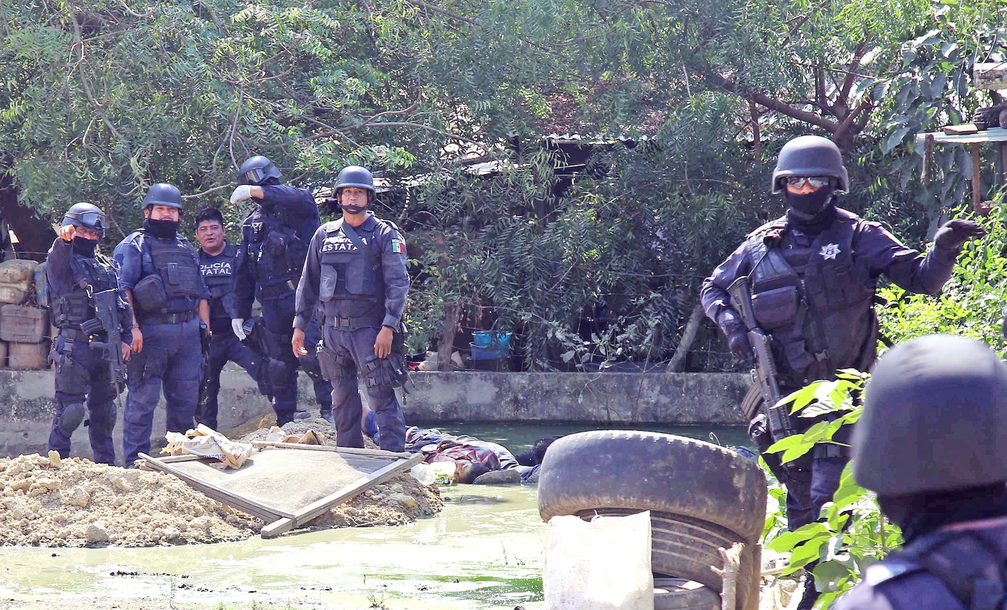 Policías estatales intentan amedrentar a periodistas para impedir que tomaran fotografías de los cuerpos de dos de los tres policías comunitarios (al fondo, abajo) abatidos en la comunidad de La Concepción en la zona rural de Acapulco Foto: Carlos Alberto Carbajal