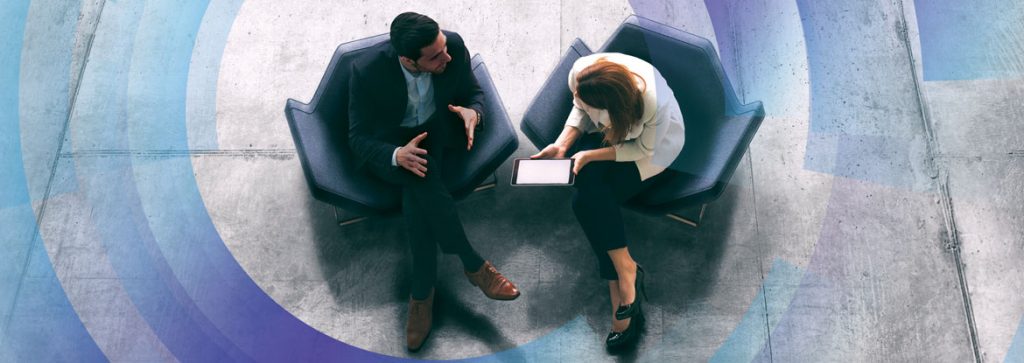 Overhead view of man and woman talking about contents on a tablet