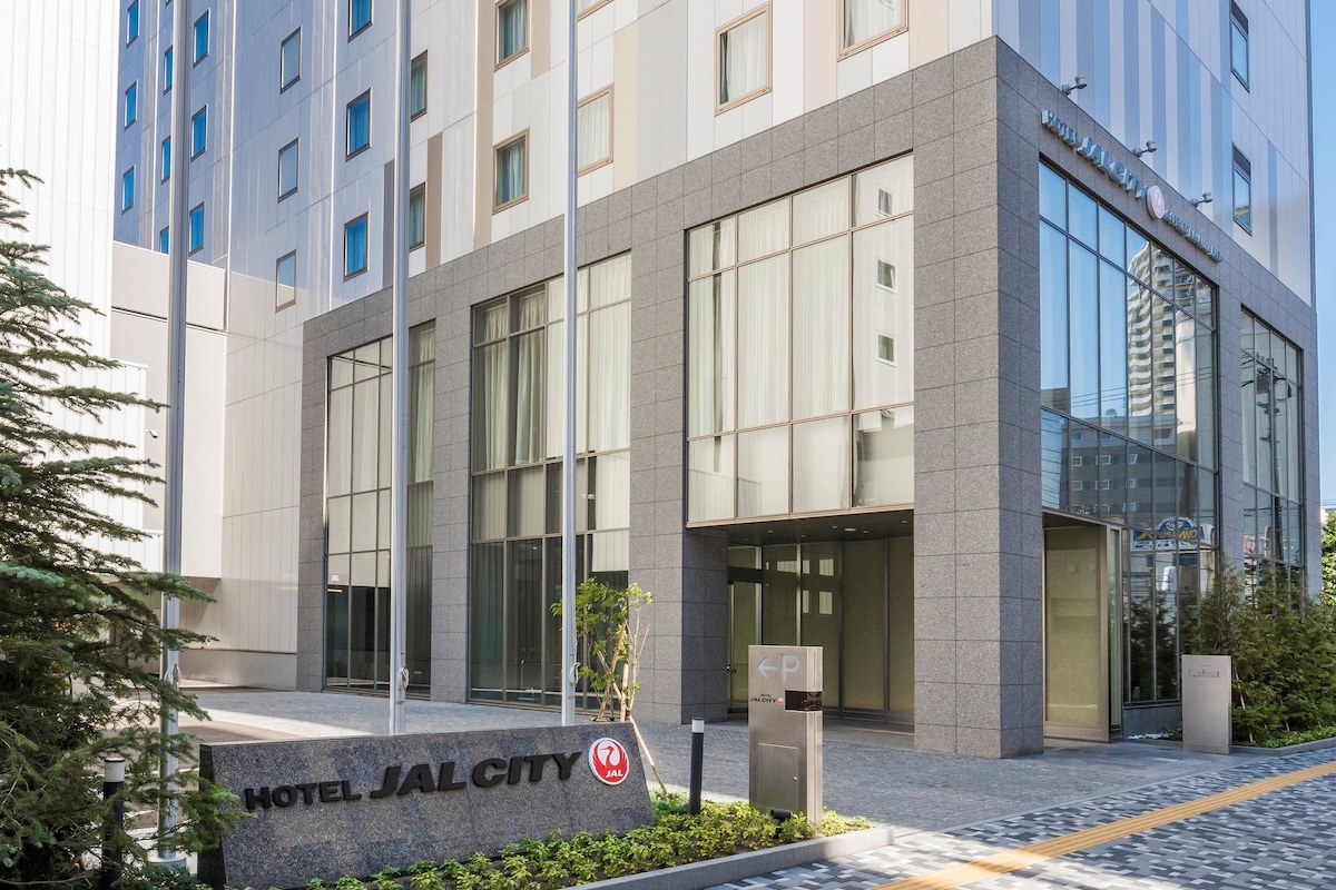 Entrance of Hotel JAL City Sapporo Nakajima Park, featuring a modern facade with large windows and clean landscaping.