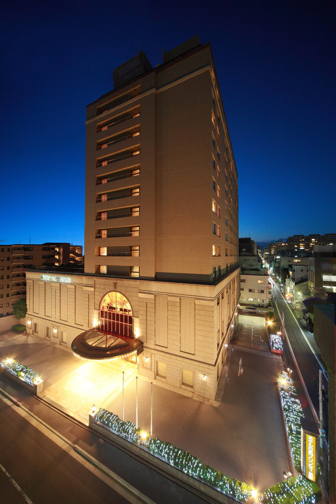 Hotel Nikko Princess Kyoto illuminated at night, featuring a grand entrance and warm lighting against a deep blue sky.