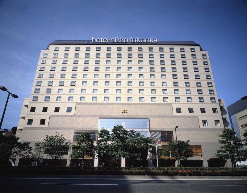 Hotel Nikko Fukuoka exterior with uniform windows and glass entrance under blue sky.