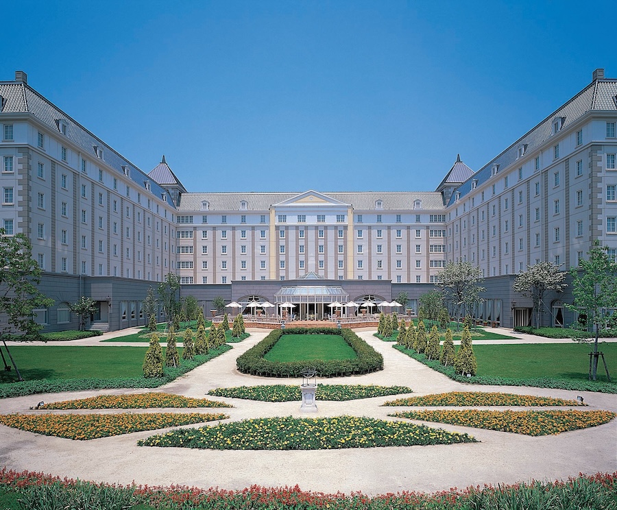 Hotel Nikko Huis Ten Bosch with grand courtyard garden and symmetrical landscaping under clear blue sky.