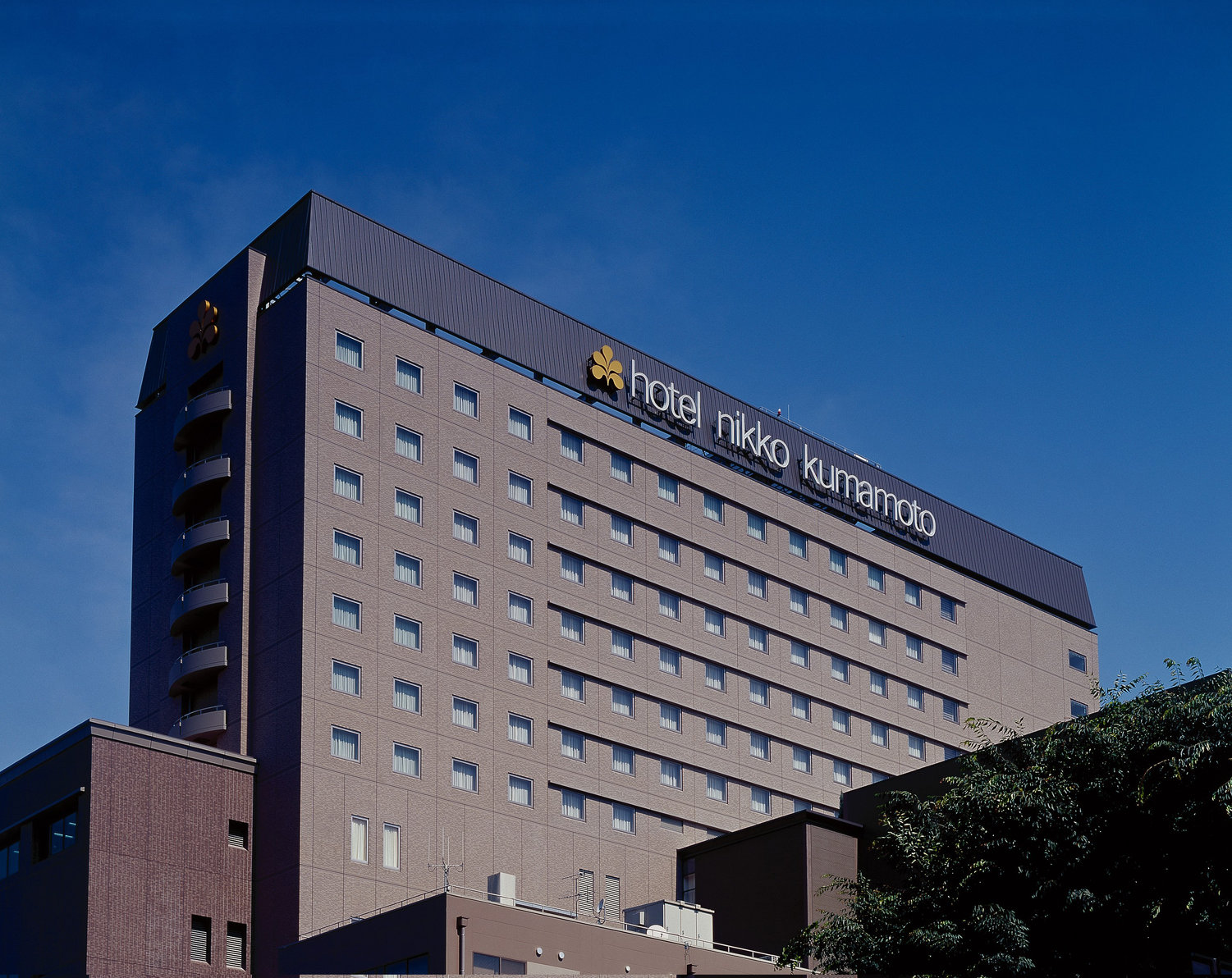 Hotel Nikko Kumamoto with its modern facade under a clear blue sky.