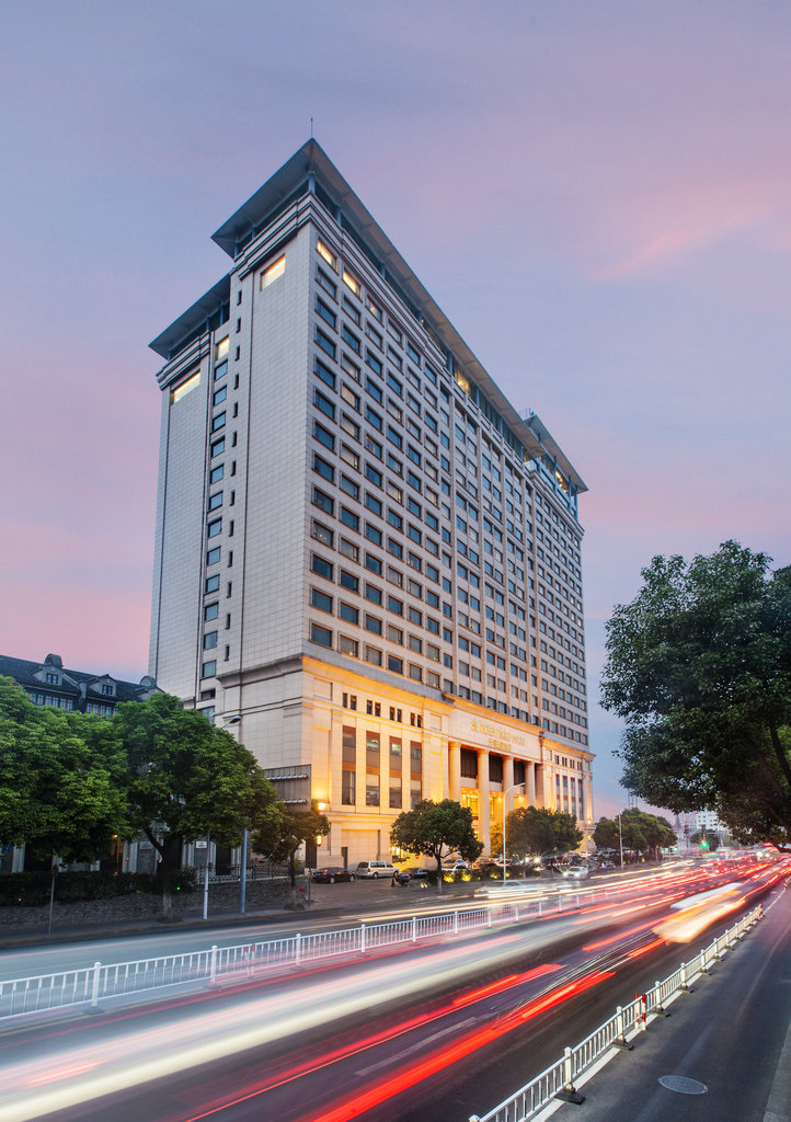 Hotel Nikko Wuxi stands tall above a busy boulevard at sunset, with elegant architecture and a glowing entrance.