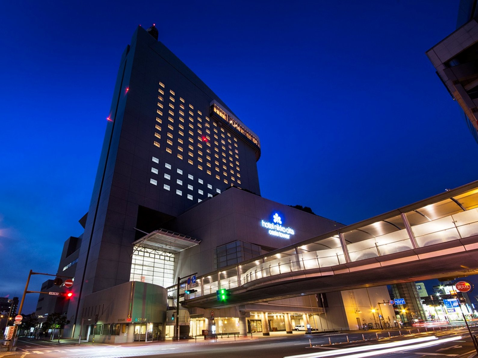 Hotel Nikko Oita Oasis Tower lit at night with skybridge over the street.