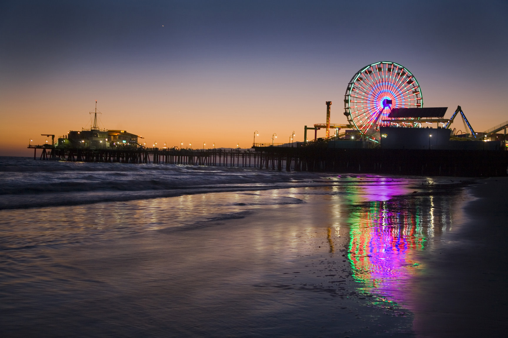 Santa Monica pier at sunset with the ocean reflecting the farris wheel lights