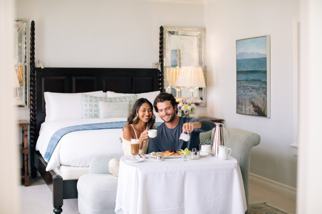 couple at the end of their bed with room service pancakes