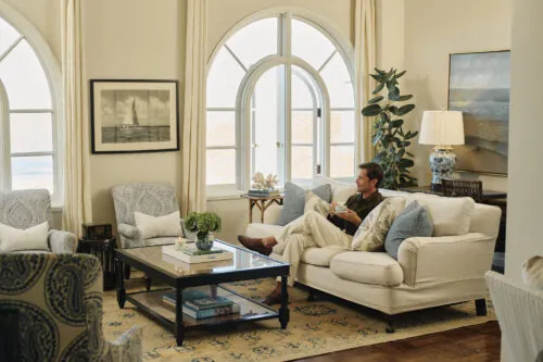 man sitting on the couch in his room by the windows drinking tea
