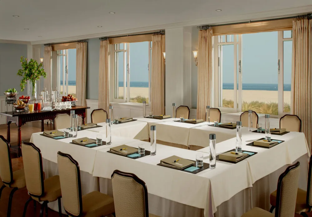A conference room offering a view of Santa Monica beach through large windows, framed by curtains.