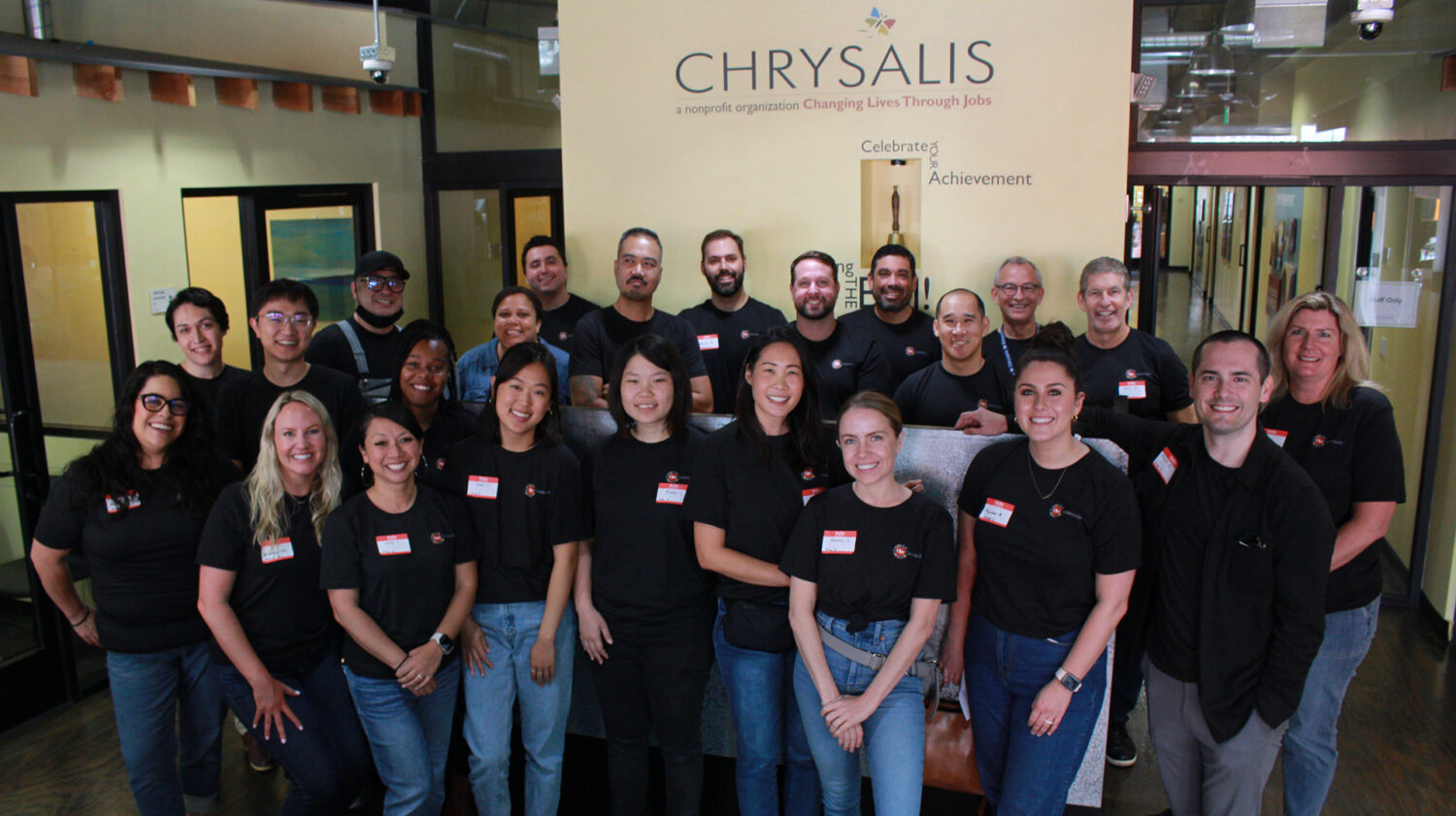A group of people wearing black t-shirts, smiling at the camera.