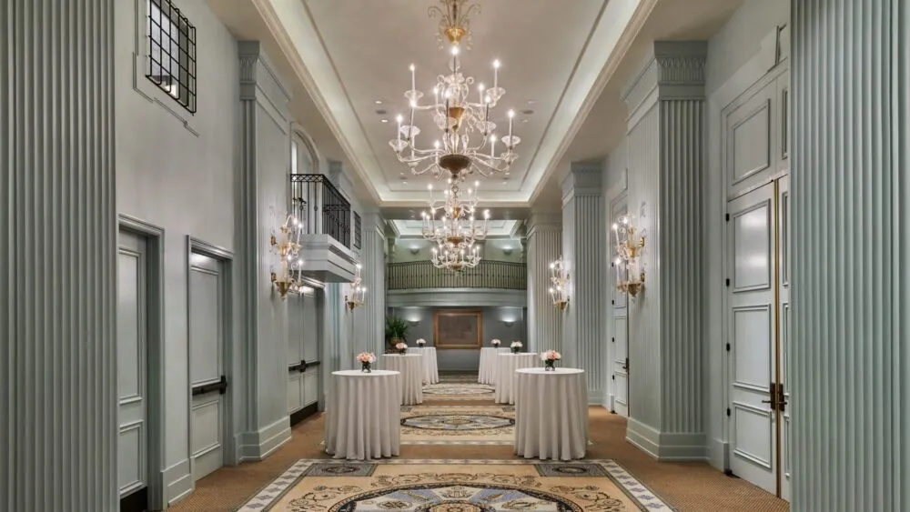 An elegant foyer with tables featuring floral arrangements, perfect for conversation during events.