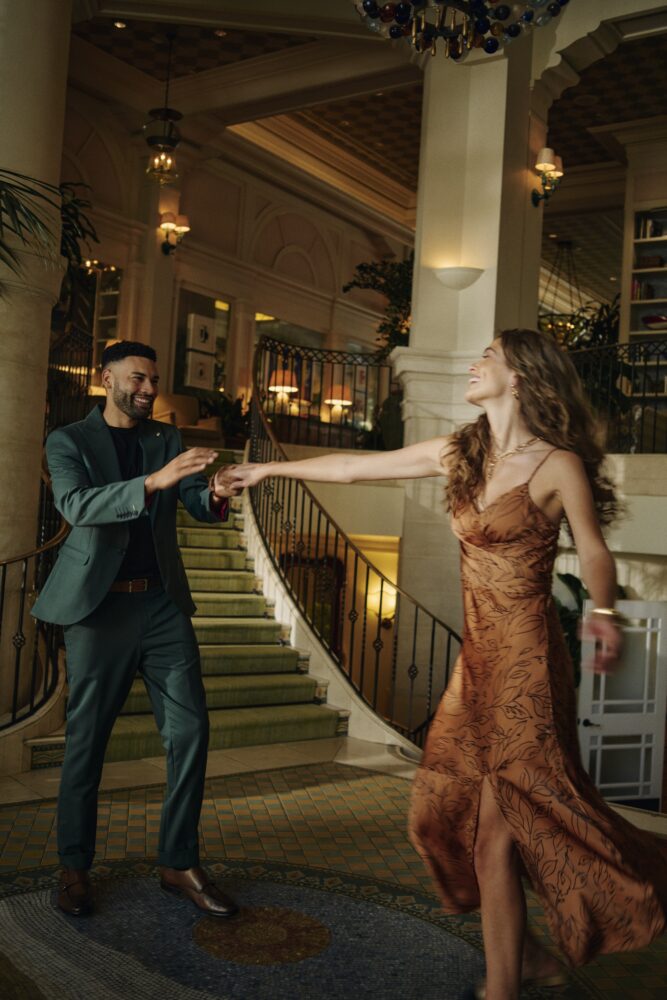 a man and a woman in a beautiful drown dress, ball dancing on the mosaic tiled floor by the staircase