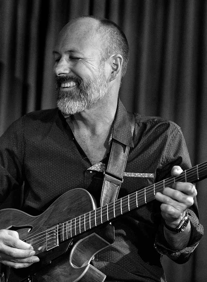 black and white photo of Mitchell Long playing the guitar
