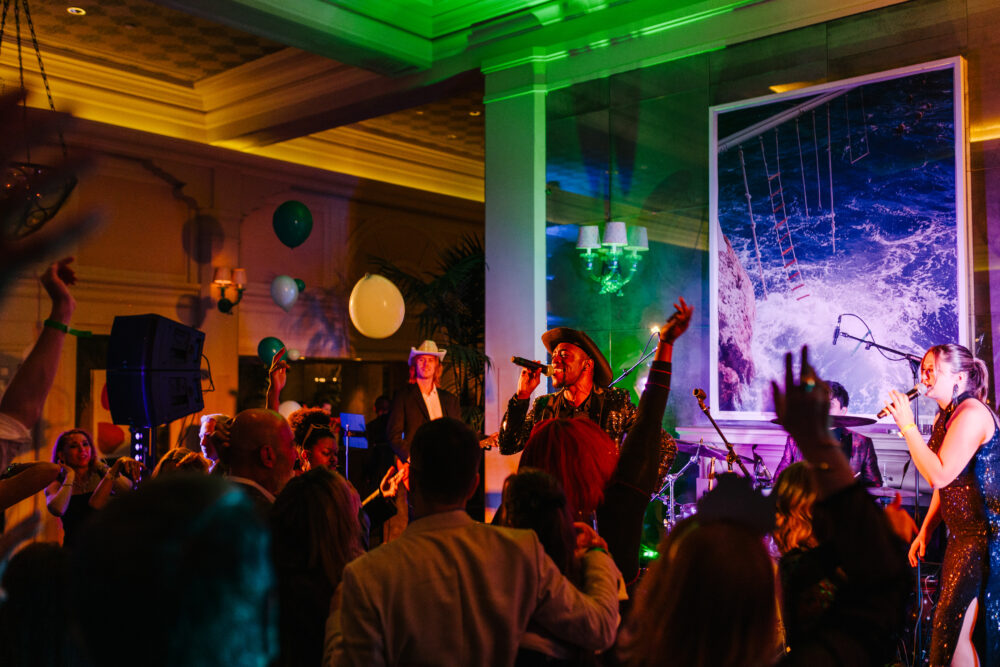 man with a microphone singing on stage at a NYE party