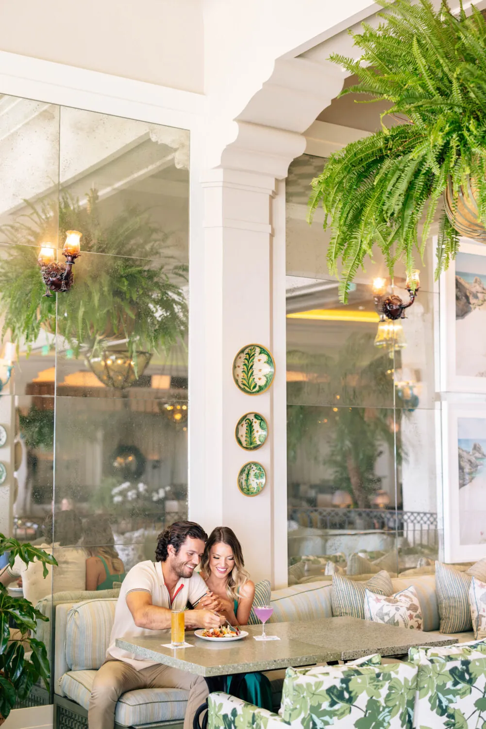 couple sitting side by side at a table with cocktails and appetizers