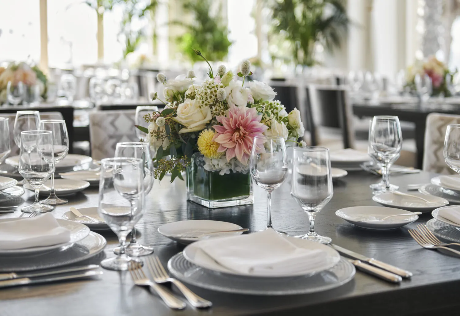 Elegant table setting with floral centerpiece, wine glasses, and dinnerware at a formal event.