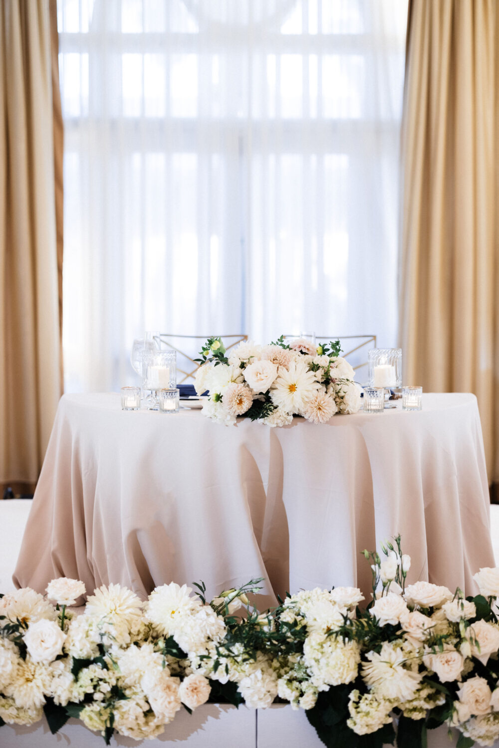 a bride and groom table at the wedding reception, with a beautiful floral display