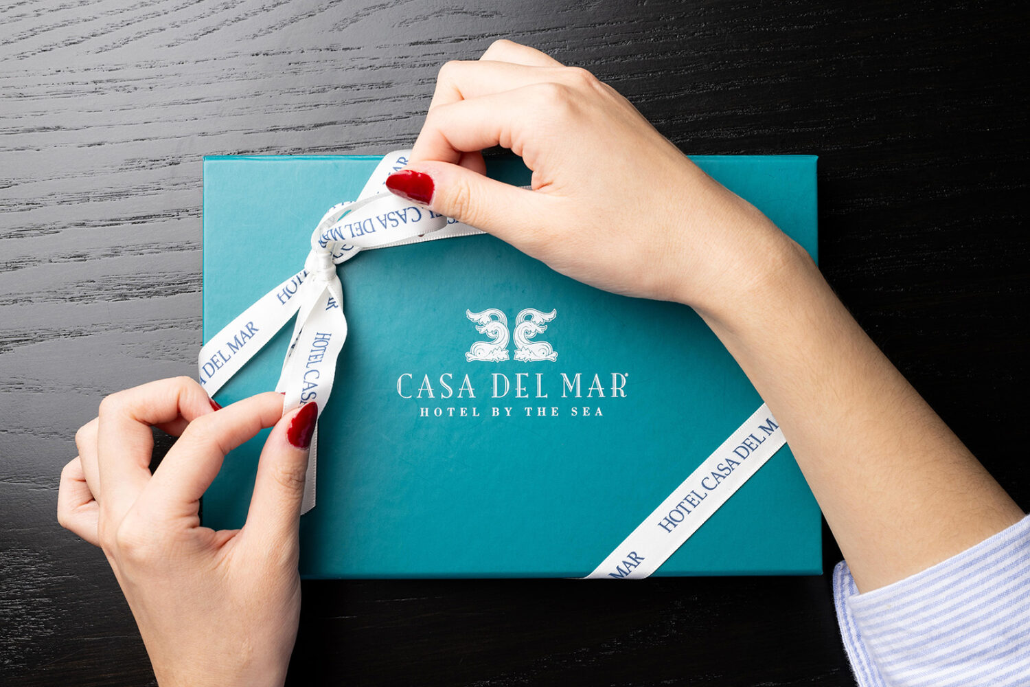 person tying a bow on a Casa del Mar giftbox