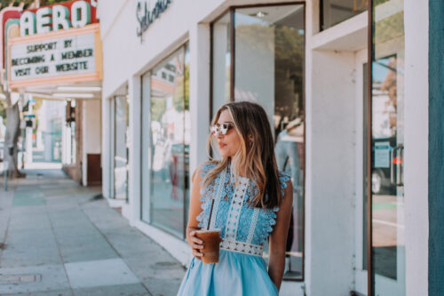 woman with iced latte standing by the shop windows